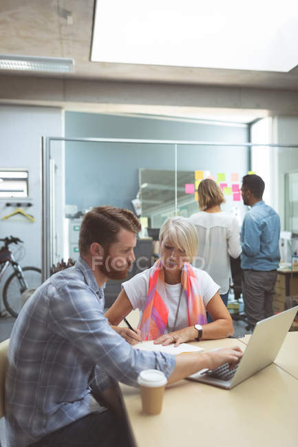 Executives discussing over laptop on table in office — Stock Photo