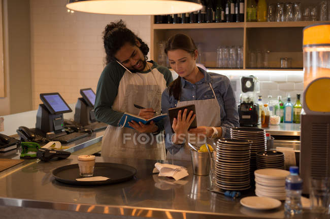 Camareros trabajando en el mostrador de café en la cafetería - foto de stock