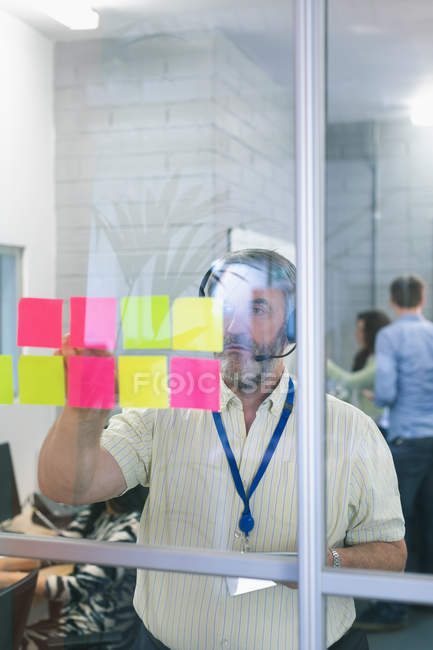 Male executive looking at sticky notes in office — Stock Photo