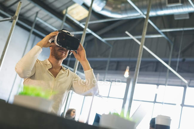 Uomo esecutivo utilizzando cuffie realtà virtuale in ufficio — Foto stock
