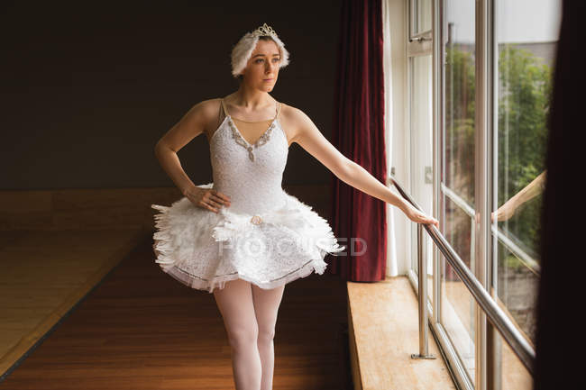 Задумчивая балерина смотрит в окно в танцевальной студии — стоковое фото