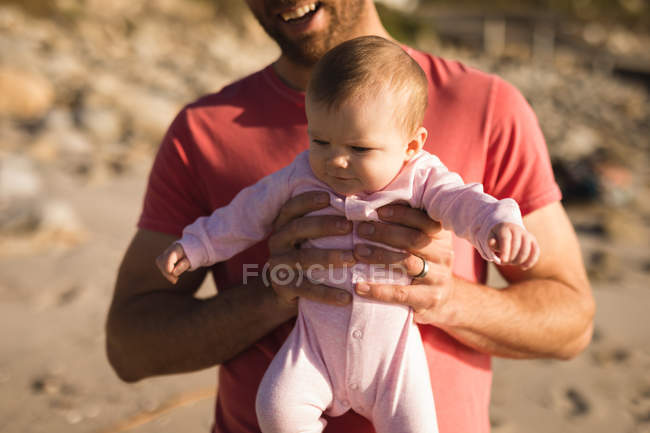 Close-up of father holding baby on beach — Stock Photo