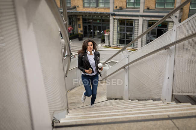 Beautiful woman running up stairs in city — Stock Photo