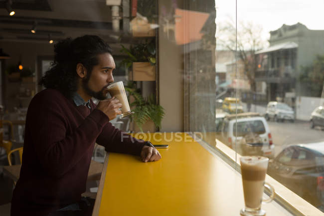 Jovem tomando café no café — Fotografia de Stock