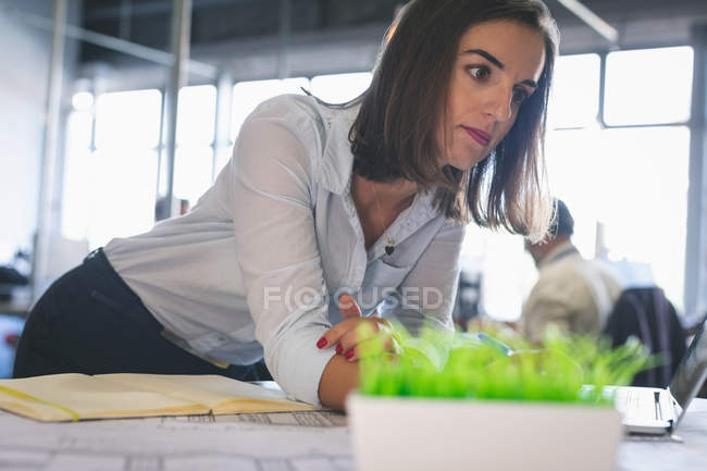 Продумана виконавча жінка стоїть за столом в офісі — стокове фото
