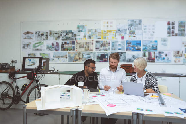 Executives discussing over blueprint at desk in office — Stock Photo