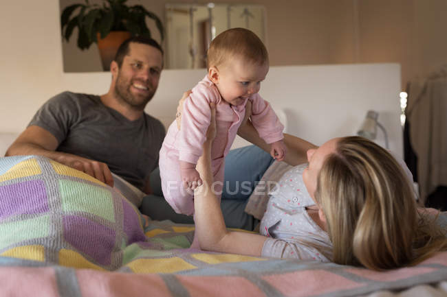 Родители веселятся с ребенком в постели дома — стоковое фото