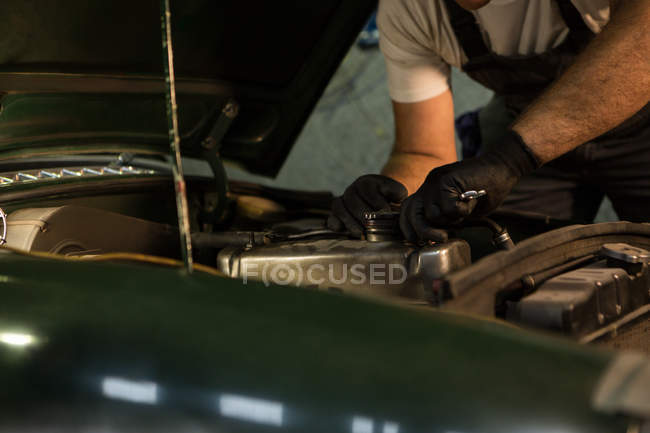 Mécanicien masculin entretenant une voiture dans le garage — Photo de stock
