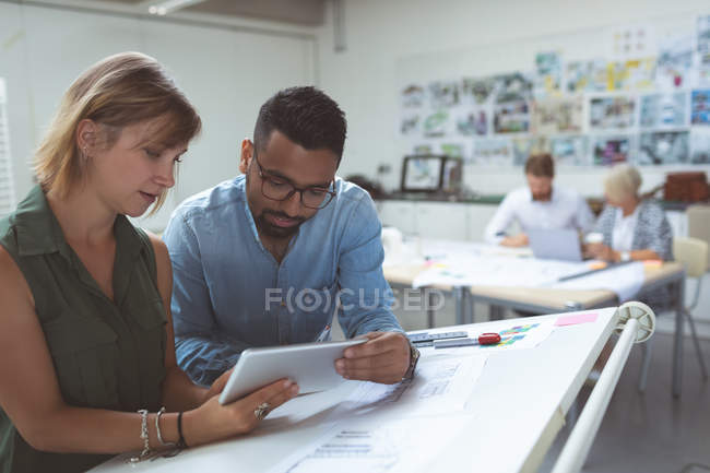 Executives discussing over digital tablet on drafting table in office — Stock Photo