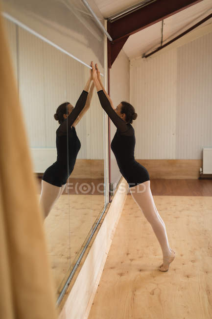 Seitenansicht der Ballerina, die sich im Studio vor dem Spiegel dehnt — Stockfoto