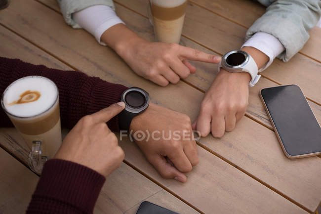 Primo piano di coppia utilizzando smartwatch al caffè all'aperto — Foto stock