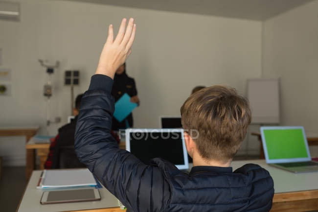 Студент поднимает руку для запроса в учебном заведении — стоковое фото