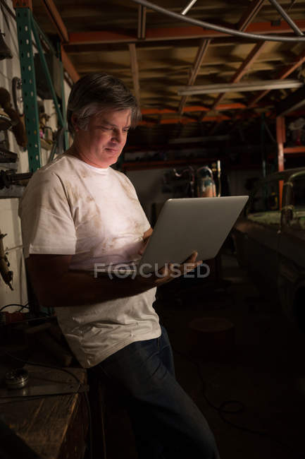 Чоловік-механік використовує ноутбук в гаражі — стокове фото