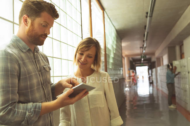 Ejecutivos discutiendo sobre tableta digital en el pasillo en la oficina - foto de stock