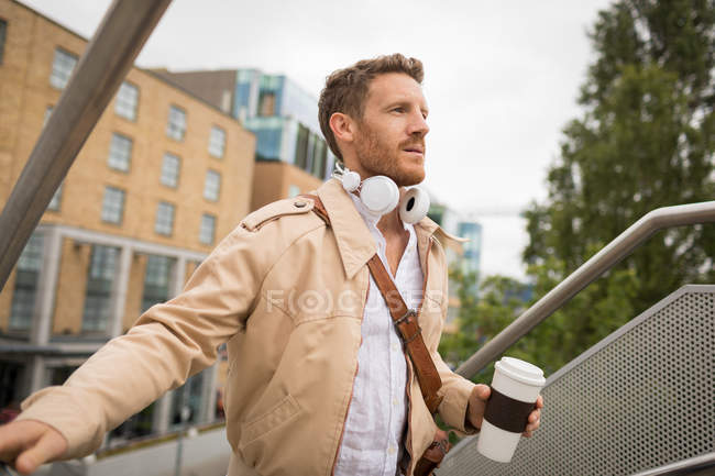 Hombre inteligente subiendo escaleras en la ciudad - foto de stock