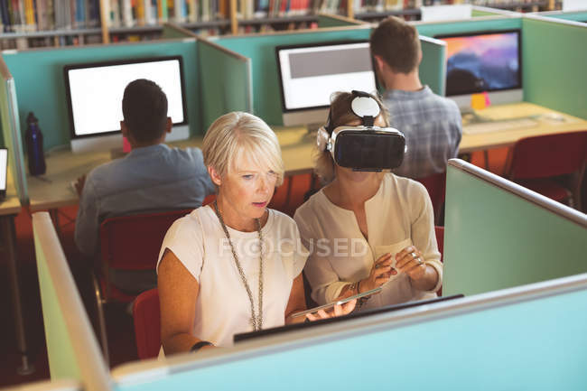 Female executives using virtual reality headset and digital tablet at desk in office — Stock Photo