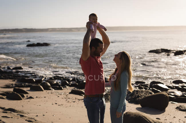 Щасливі батьки грають з дитиною на пляжі — стокове фото