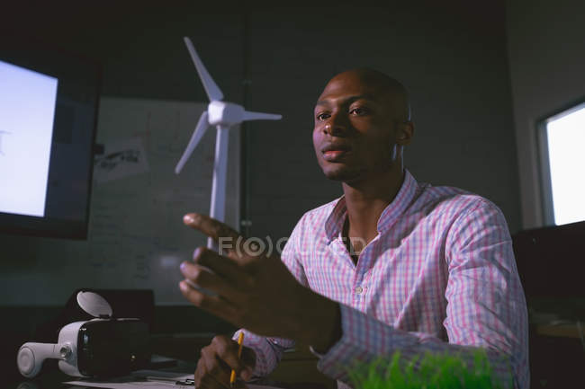 Executivo masculino examinando um modelo de moinho de vento no escritório — Fotografia de Stock