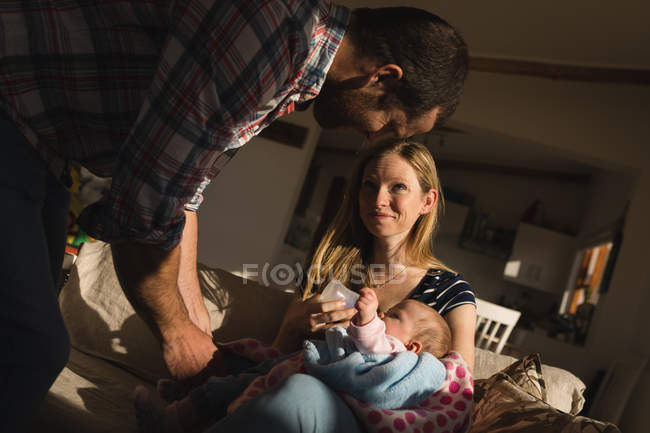 Матері годування свою дитину, а батько, граючи з дитиною на дивані в домашніх умовах — стокове фото
