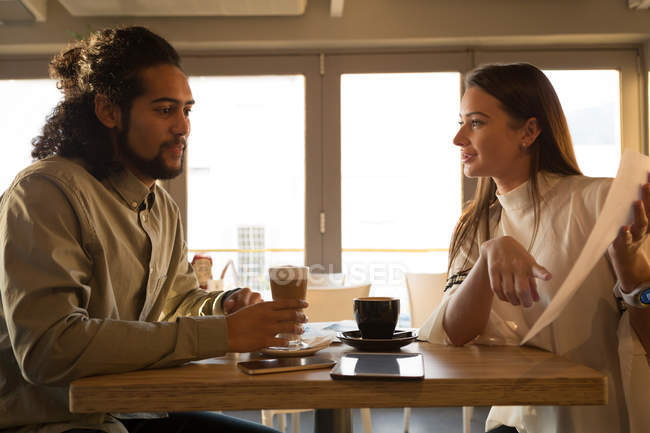 Пара обговорює паперовий документ у кафе — стокове фото
