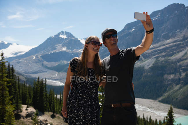Пара бере селфі з мобільним телефоном у сільській місцевості — стокове фото