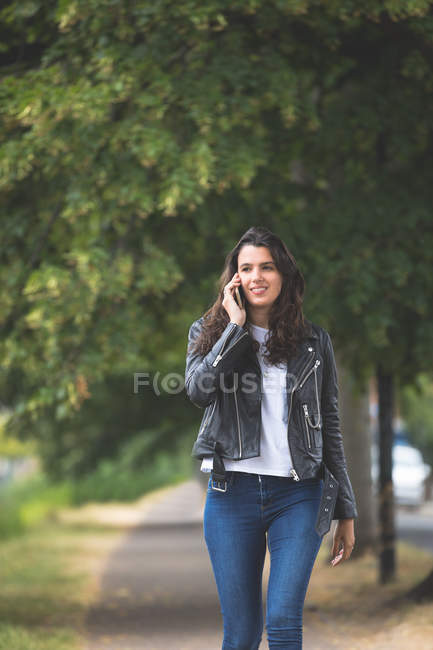 Hermosa mujer hablando en el teléfono móvil mientras camina en la calle - foto de stock
