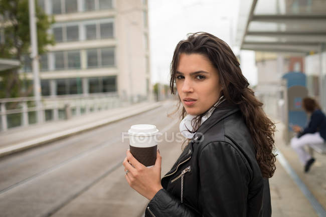 Frau trinkt Kaffee auf Bahnsteig am Bahnhof — Stockfoto