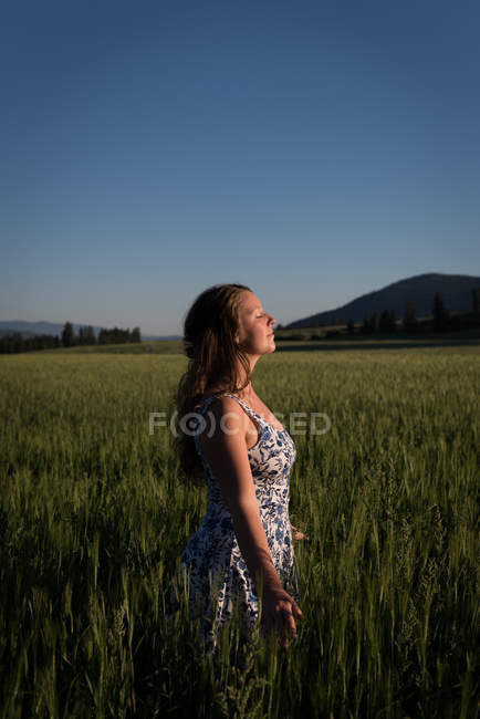 Beautiful woman standing with eyes closed in the field — Stock Photo