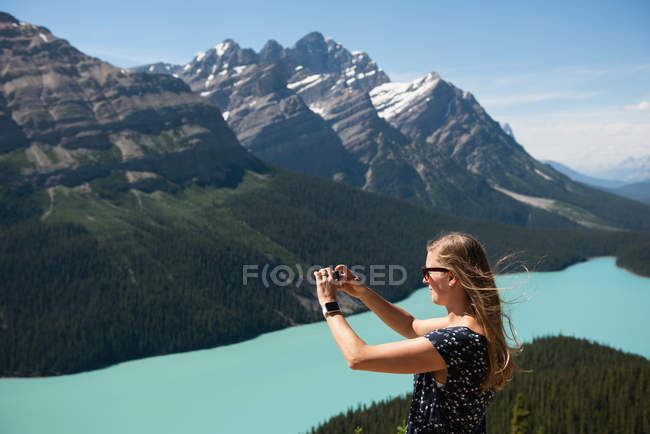 Frau klickt an einem sonnigen Tag mit dem Handy auf Bilder — Stockfoto