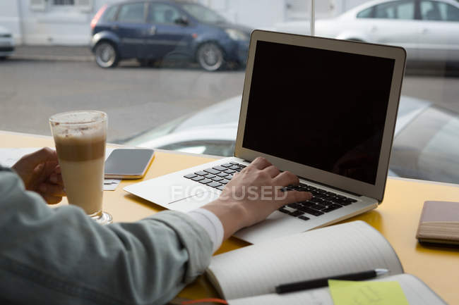 Primer plano de la mujer que usa el ordenador portátil en la cafetería - foto de stock
