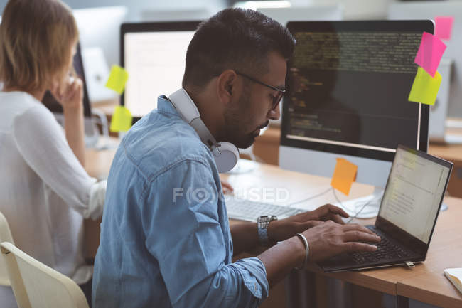 Male executive using laptop at desk in office — Stock Photo