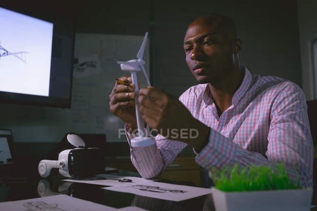 Executivo masculino examinando um modelo de moinho de vento no escritório — Fotografia de Stock