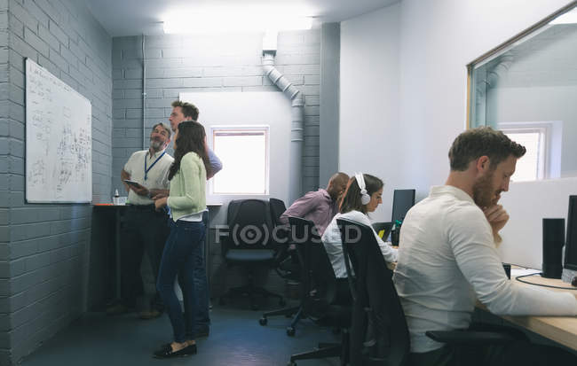 Empresários discutindo sobre quadro branco no escritório — Fotografia de Stock