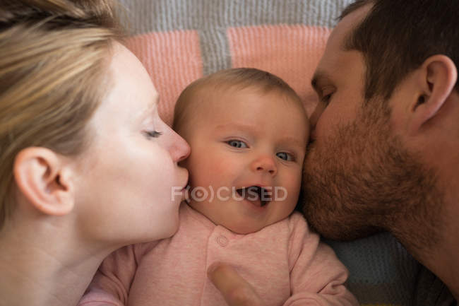 Gros plan des parents embrassant bébé au lit à la maison — Photo de stock