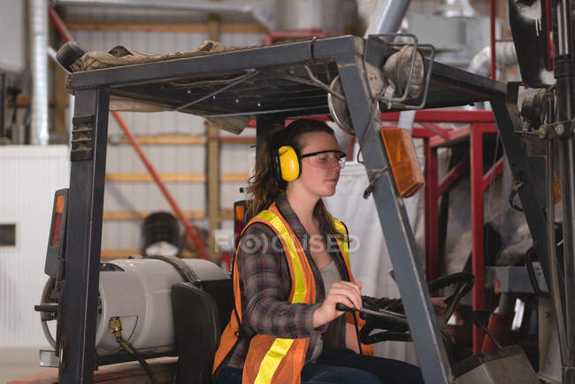 Female worker driving forklift at warehouse — Stock Photo