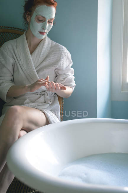 Femme appliquant la crème dans la salle de bain à la maison — Photo de stock