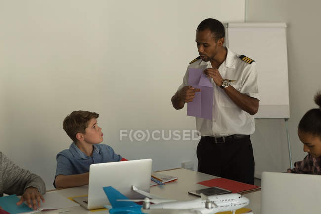 Молодой пилот обучает детей в учебном заведении — стоковое фото
