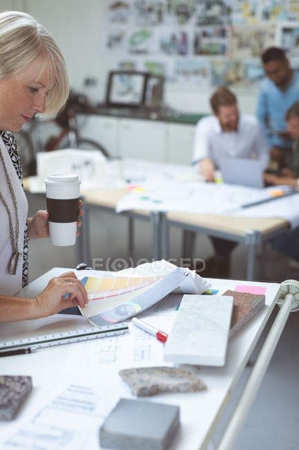 Muestra de color de comprobación ejecutiva femenina en la mesa de dibujo en la oficina - foto de stock