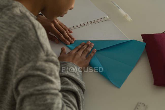 Primo piano di bambino che fa aereo di carta con carta artigianale in istituto di formazione — Foto stock