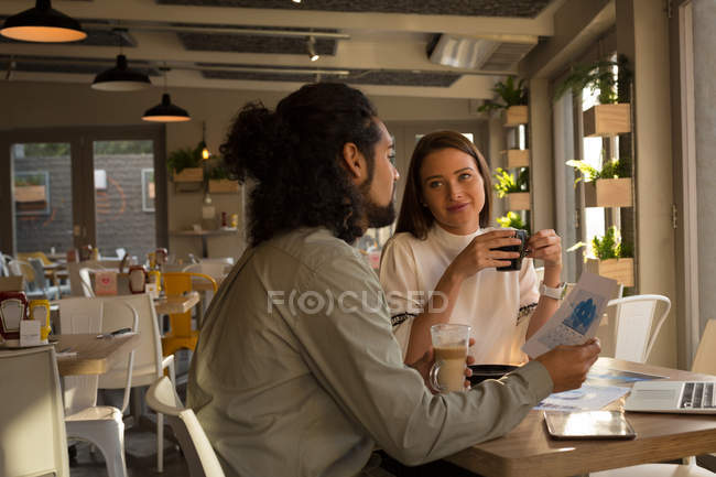 Führungskräfte diskutieren im Café über Dokumentenpapier — Stockfoto
