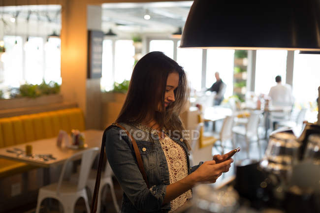 Усміхнена жінка використовує мобільний телефон у кафе — стокове фото