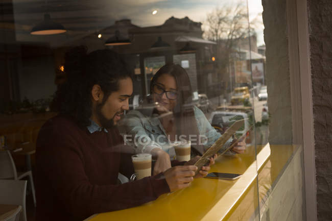 Casal jovem discutindo cartão de menu no café — Fotografia de Stock