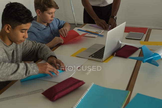 Enfants fabriquant un avion en papier avec du papier artisanal dans un institut de formation — Photo de stock
