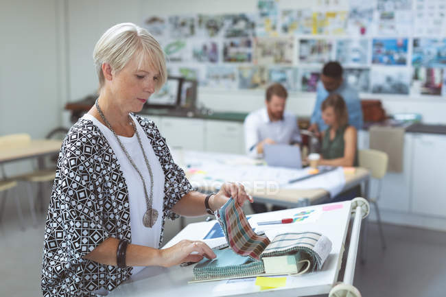 Weibliche Führungskräfte prüfen Katalog auf dem Schreibtisch im Büro — Stockfoto