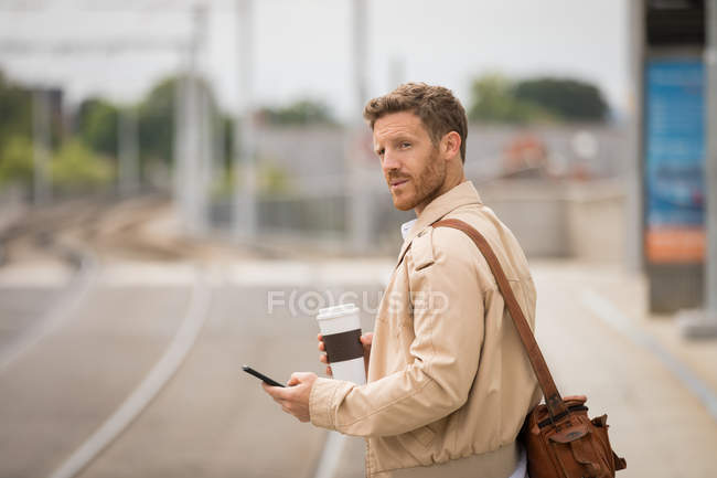 Homem inteligente usando telefone celular na plataforma na estação ferroviária — Fotografia de Stock