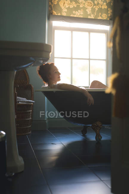 Mulher tomando banho na banheira no banheiro — Fotografia de Stock