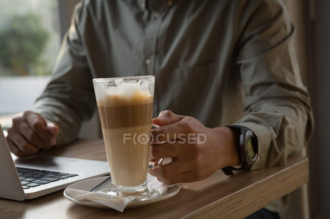 Средняя секция человека, держащего кофейную кружку в кафе — стоковое фото