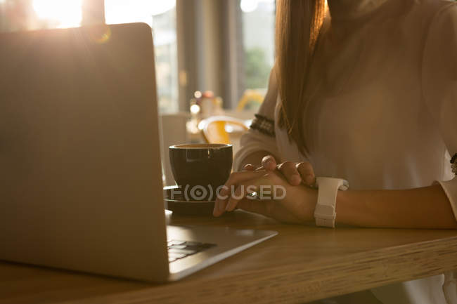 Середина жінки, використовуючи смарт-годинник в кафе — стокове фото