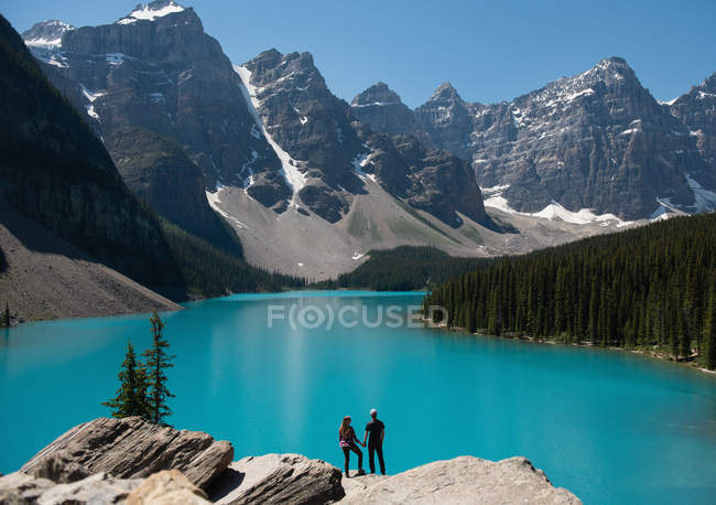Vue arrière d'un couple debout sur un rocher près d'une rivière — Photo de stock