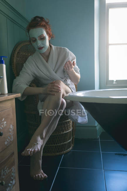 Frau cremt sich zu Hause im Badezimmer ein — Stockfoto